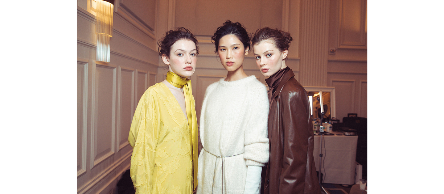 Three models posing in muted tone outfits showcasing casual elegance at NYFW F/W 2024.